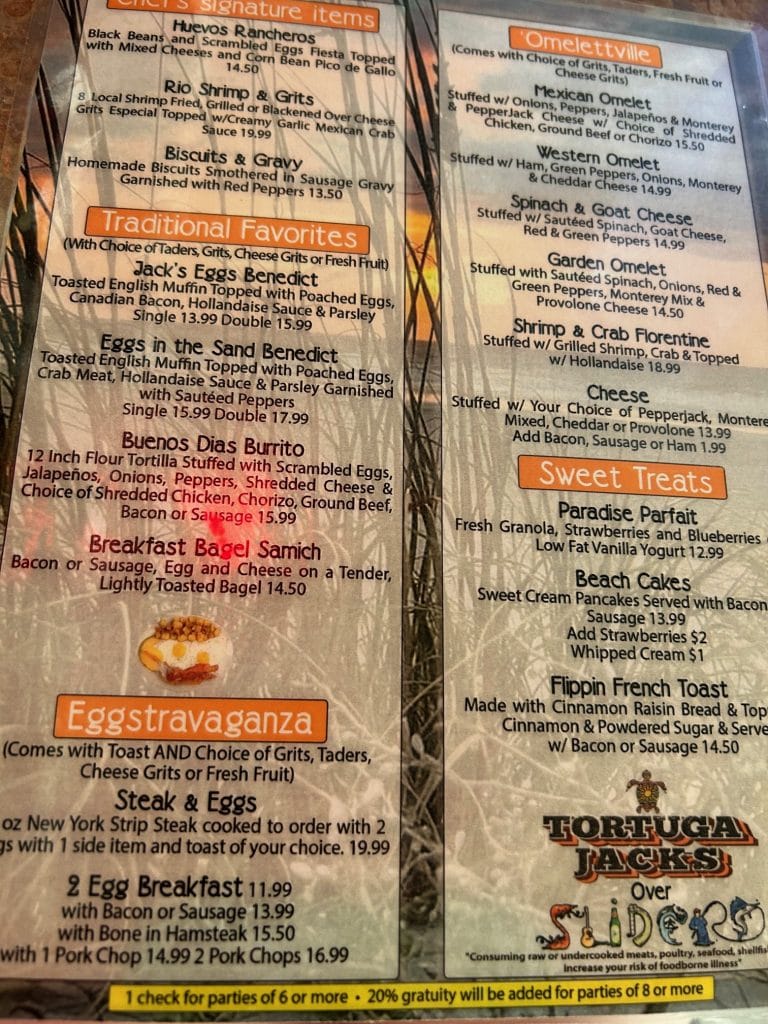 Breakfast menu from Tortuga Jack’s in Amelia Island featuring categories like Omelettville, Traditional Favorites, Sweet Treats, Signature Items, and Eggstravaganza. Dishes include shrimp and grits, huevos rancheros, crab Florentine, sweet cream pancakes, and a variety of omelets, with pricing and sides listed.