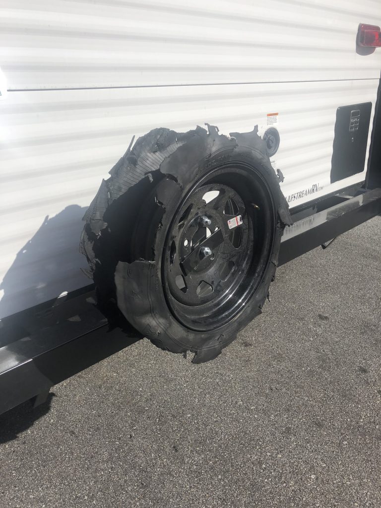 tire that had a blowout that is now mounted on the back of an RV where the spare tire belongs