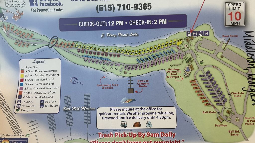 Illustrated campground map of Elm Hill RV Resort on J. Percy Priest Lake, showing color-coded RV site sections from deluxe waterfront to inland sites, along with labeled amenities like a dog park, pool, restrooms, bathhouse, laundry, and dumpsters. The map highlights the swimming area, day-use docks, check-in and exit gates, and boat ramp, with site numbers clearly marked and directional arrows for entry and traffic flow.