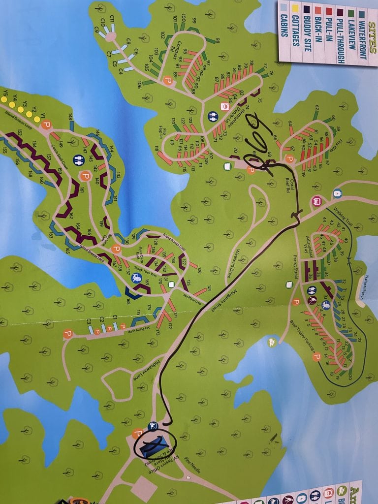 Colorful illustrated campground map of Margaritaville Lake Lanier showing waterfront, lakeview, pull-through, back-in, and buddy RV sites, along with cottages and cabins. Roads, parking areas, restrooms, and amenities are marked, with sections divided by inlets of blue water and green wooded areas.