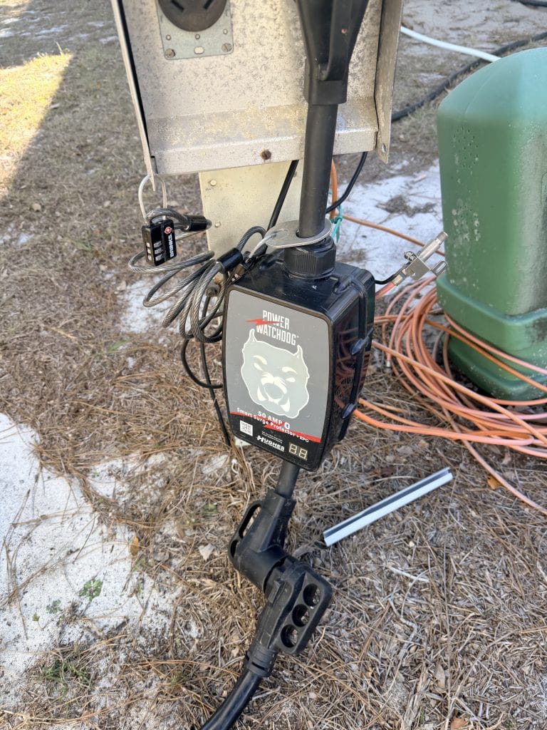 Power Watchdog 50 amp surge protector connected between an RV power cord and a campground electrical pedestal. The device helps protect an RV from power surges, wiring faults, and unsafe electrical conditions that could affect onboard systems and appliances.